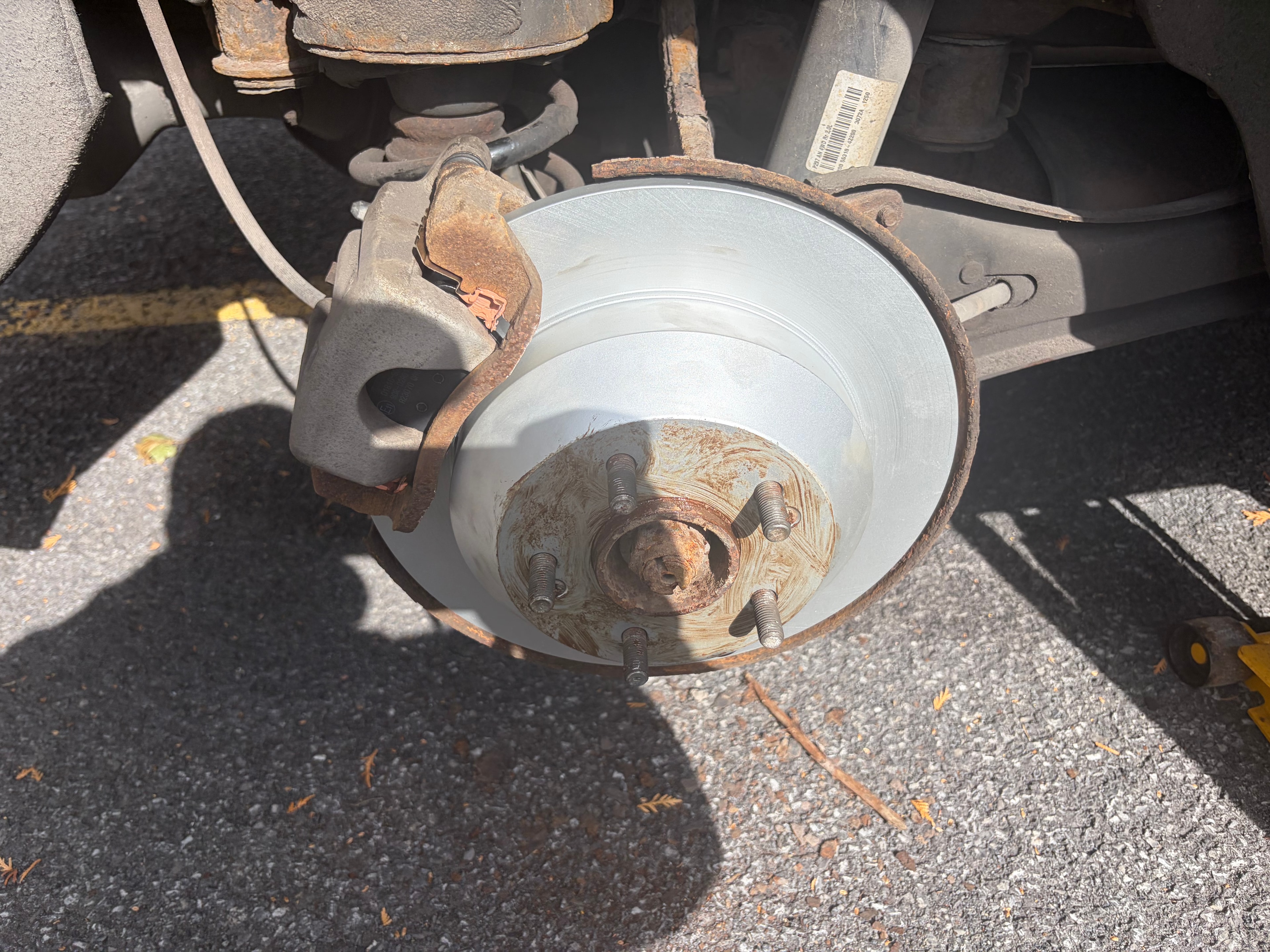 Disque de frein neuf argenté installé sur le véhicule — résultat après remplacement complet par Caron Précision Automobile
