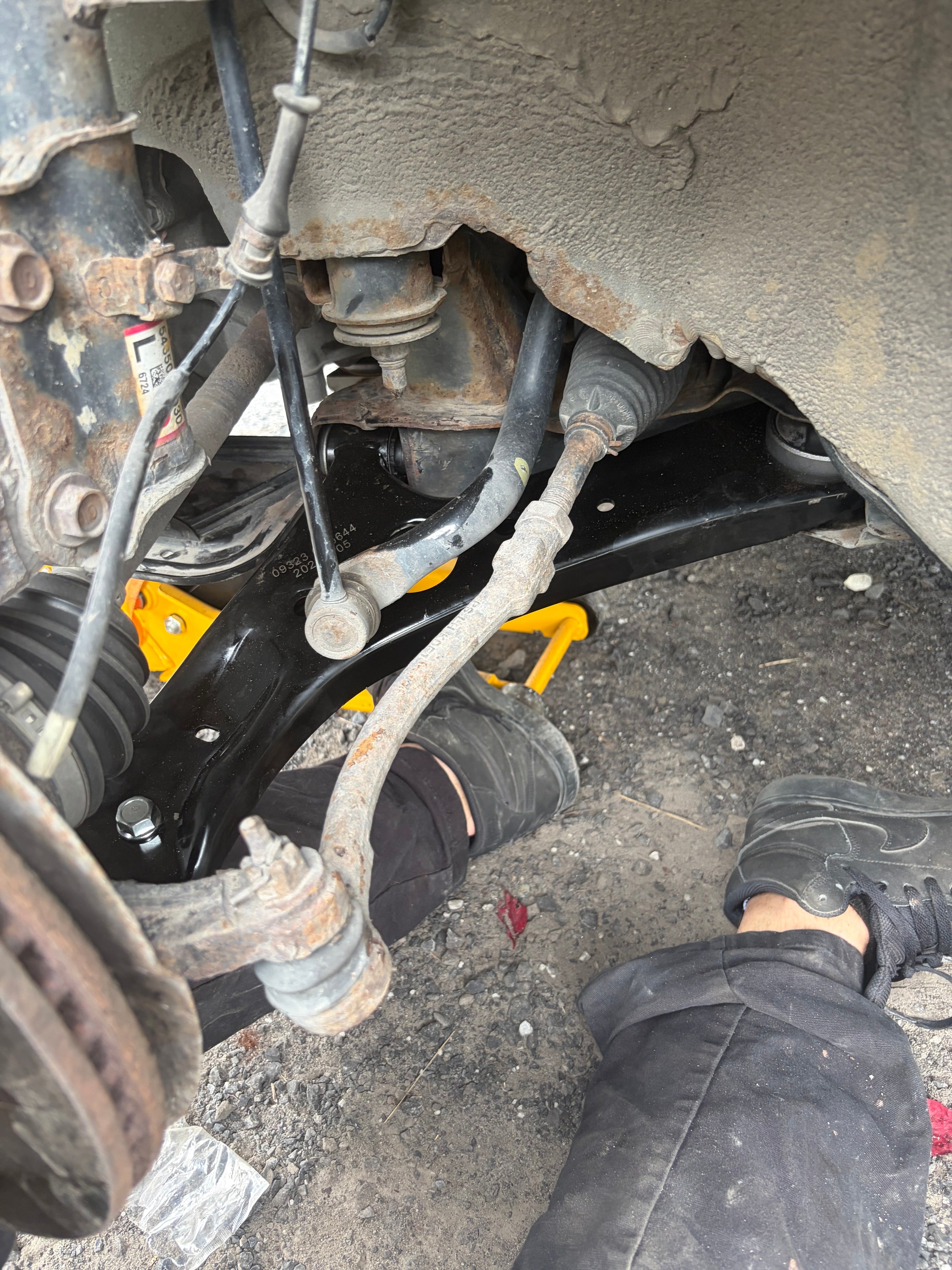 Bras de suspension neuf noir installé sous le véhicule — résultat après remplacement par Caron Précision Automobile